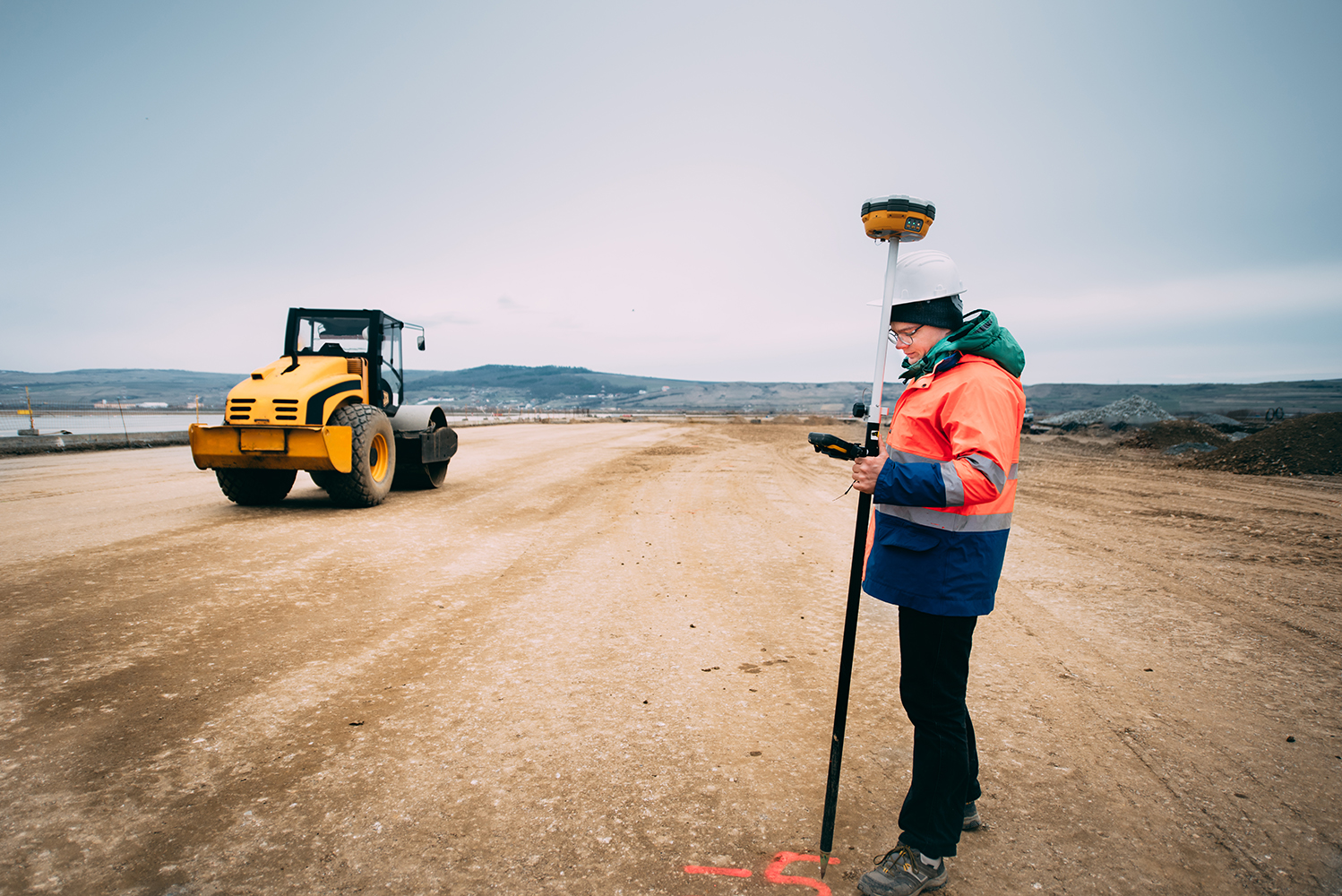 Portrait of engineer on construction site, surveyor using gps sy